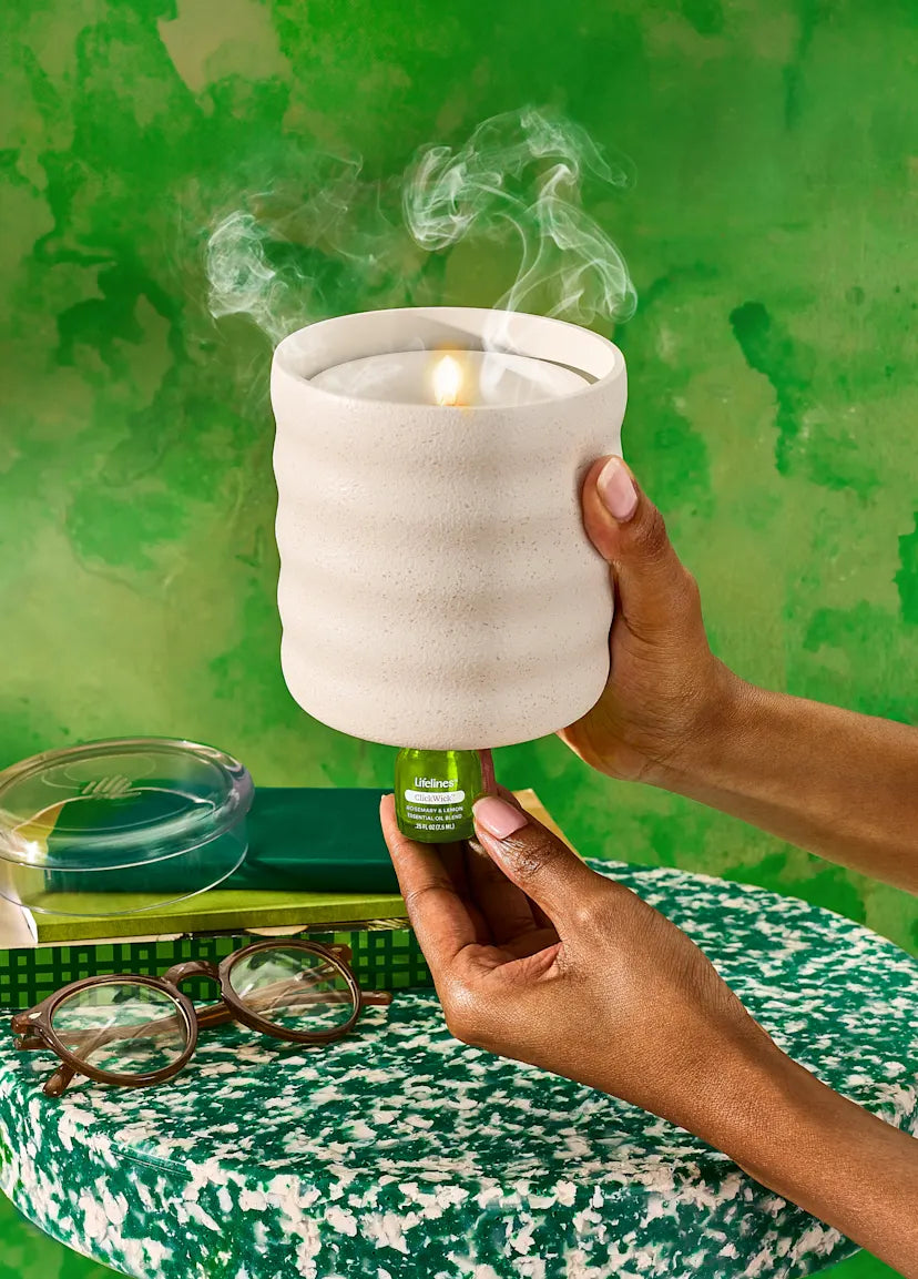 Hand holding Lifelines ceramic diffuser with smoke against a green background